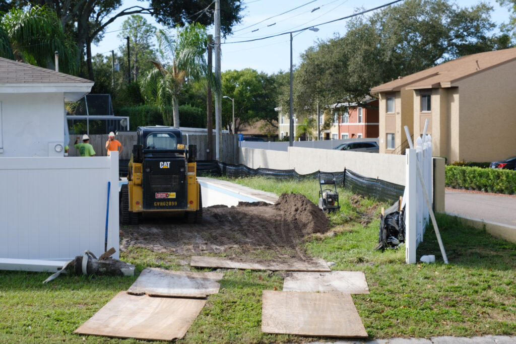 two workers skid steer pool